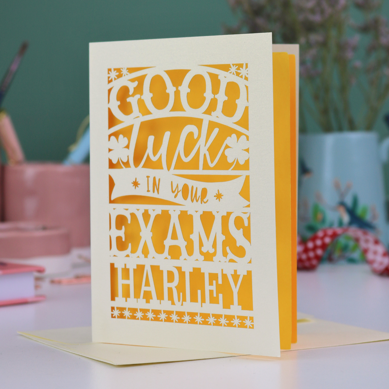 Greeting card with 'Good luck in your exams Harley' text on a blurred background