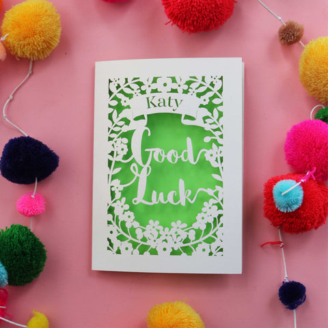 Papercut personalised Good Luck card. Cut from cream card with a bright green background. Shows the words good luck surrounded with flowers and a banner for the name. - A5 / Bright Green