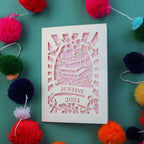 A cream and pink cut out graduation card featuring a cap and name