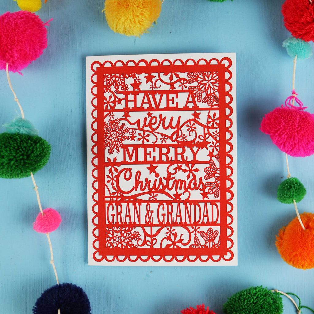 Red Christmas card with personalized message surrounded by colourful pom-poms on a blue background