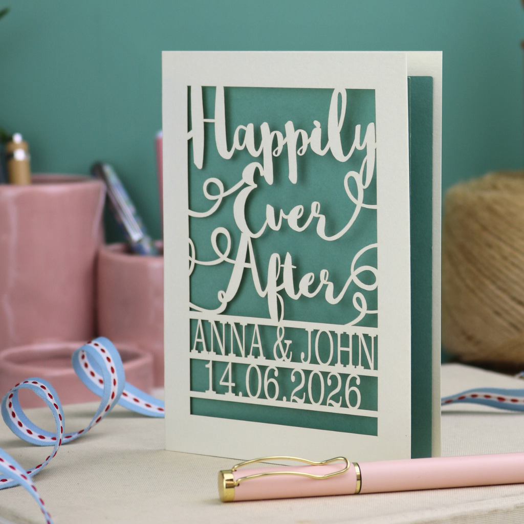 A laser cut wedding card with cut out text, 'Happily Ever After' in a script font, personalised with 'Anna & John, 14.06.2026'