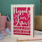 A laser cut wedding card with cut out text, 'Happily Ever After' in a script font, personalised with 'Anna & John, 14.06.2026'