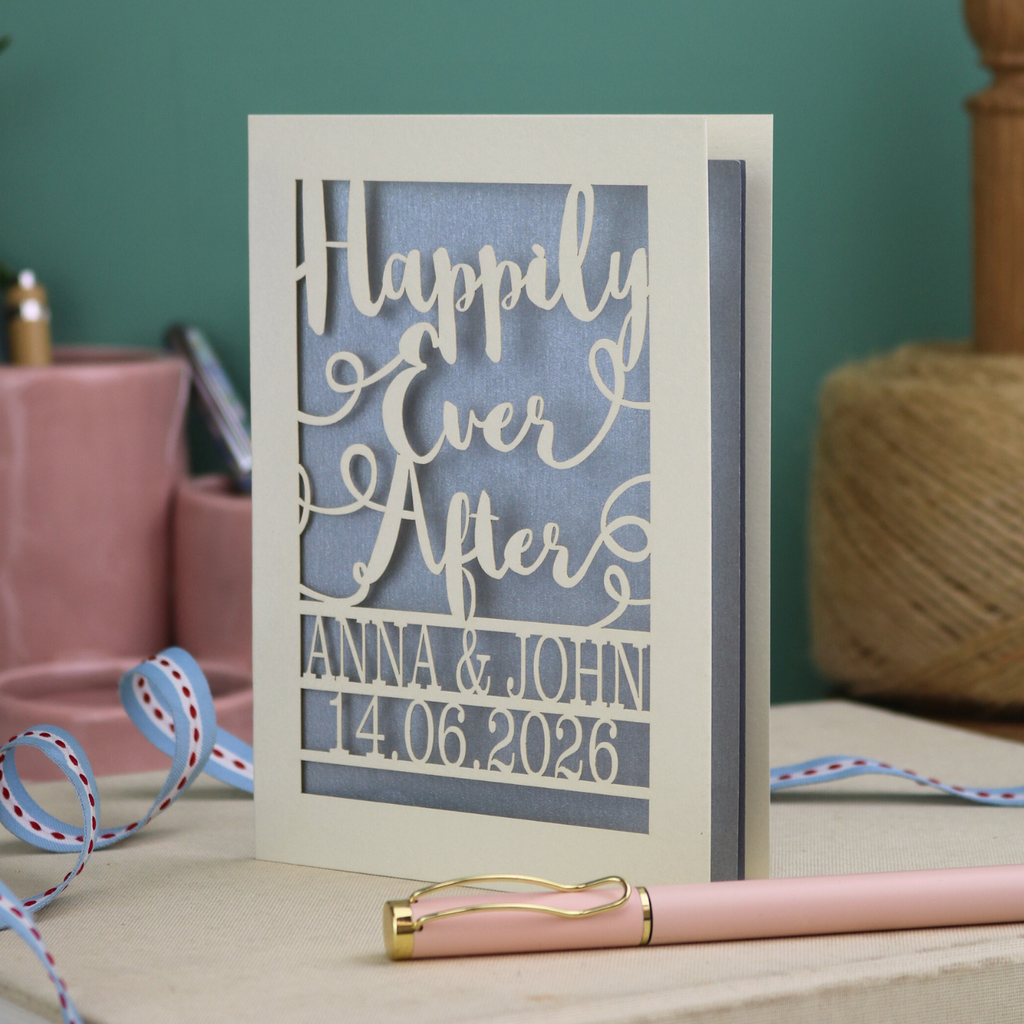 A laser cut wedding card with cut out text, 'Happily Ever After' in a script font, personalised with 'Anna & John, 14.06.2026'