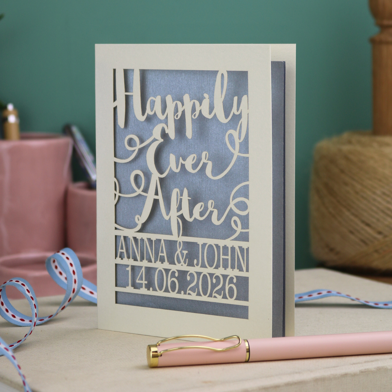 A laser cut wedding card with cut out text, 'Happily Ever After' in a script font, personalised with 'Anna & John, 14.06.2026'