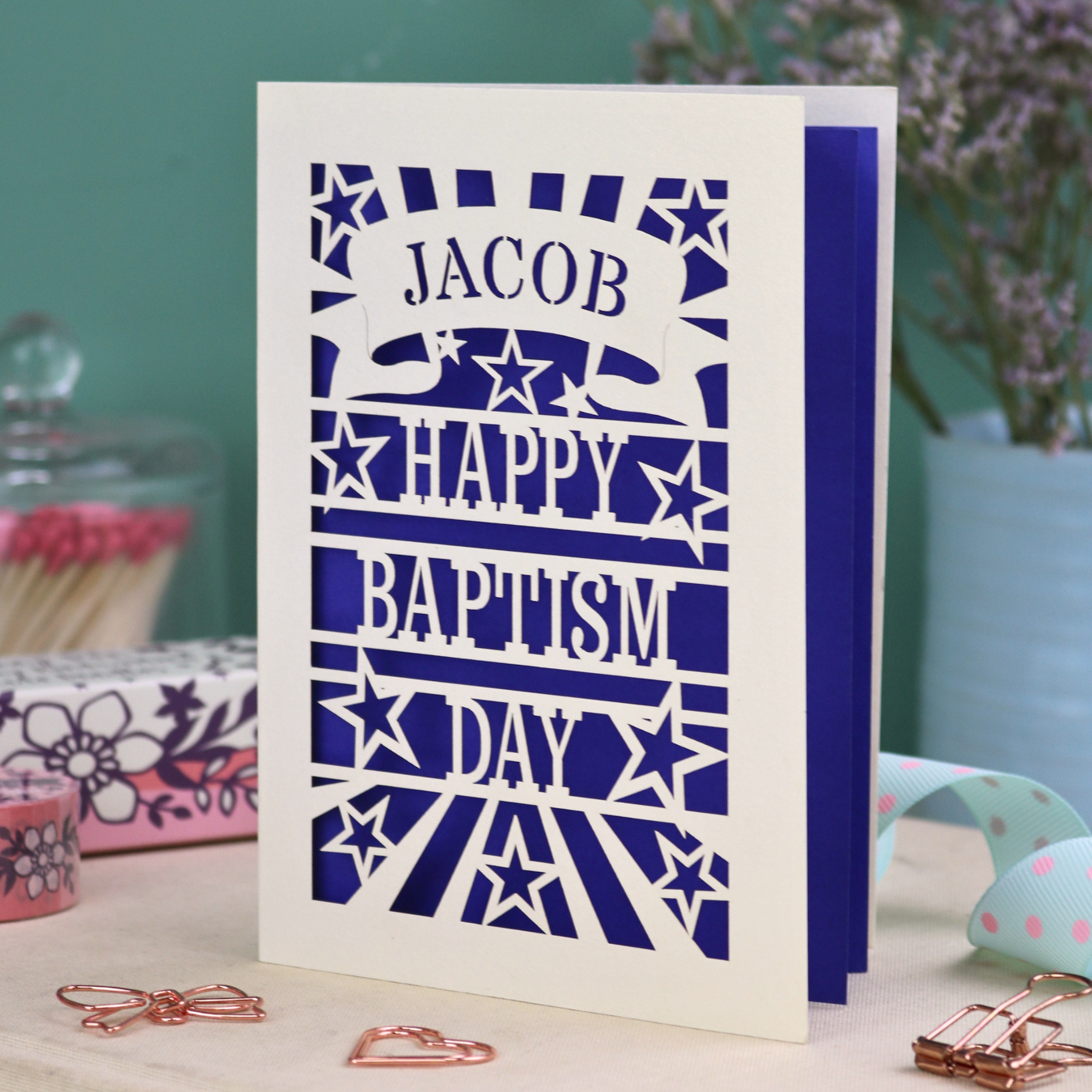 Personalised Baptism Card with 'Happy Baptism Day' text and stars on a decorative background, personalised with a stencil-font cut out name in a banner at the top
