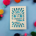 Laser Cut card with 'Happy Bar Mitzvah Noah' text on a blue background with colourful pom-poms.