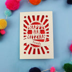 Laser Cut card with 'Happy Bar Mitzvah Noah' text on a blue background with colourful pom-poms.