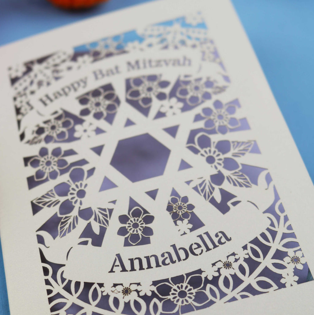Decorative Bat Mitzvah card with floral pattern and 'Happy Bat Mitzvah Annabella' text on a blue background