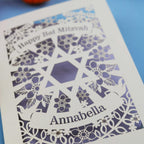 Decorative Bat Mitzvah card with floral pattern and 'Happy Bat Mitzvah Annabella' text on a blue background