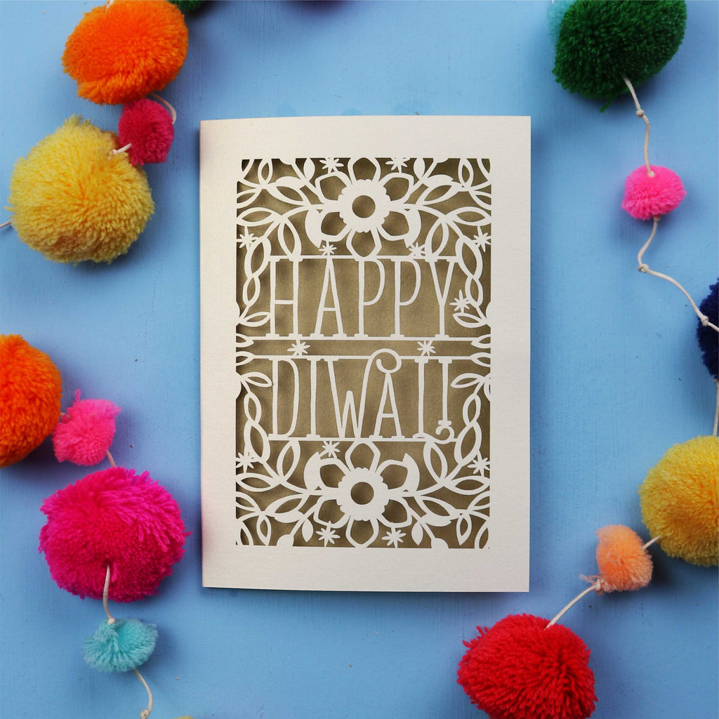 Laser Cut Diwali Card with 'Happy Diwali' design surrounded by colourful pom-poms on a blue background