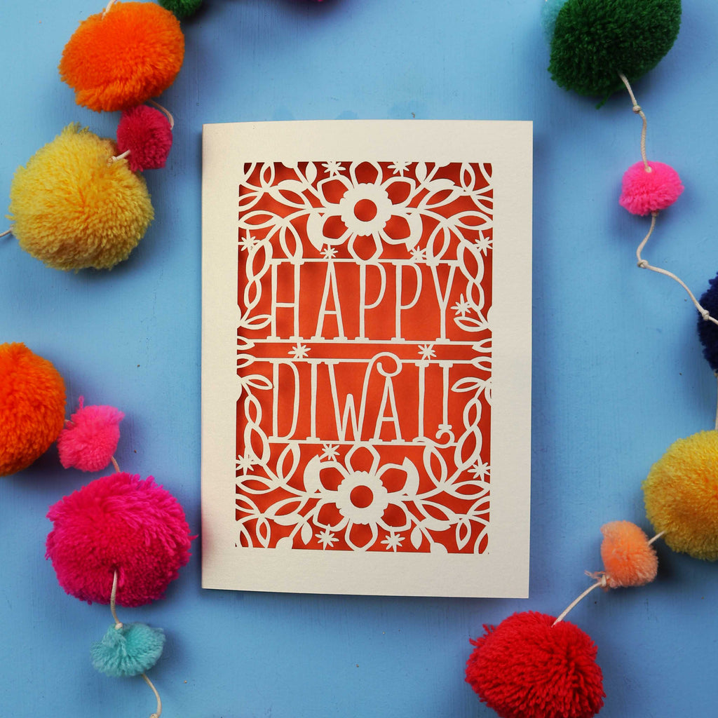 Laser Cut Diwali Card with 'Happy Diwali' design surrounded by colourful pom-poms on a blue background