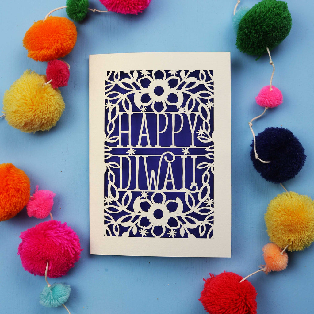 Laser Cut Diwali Card with 'Happy Diwali' design surrounded by colourful pom-poms on a blue background