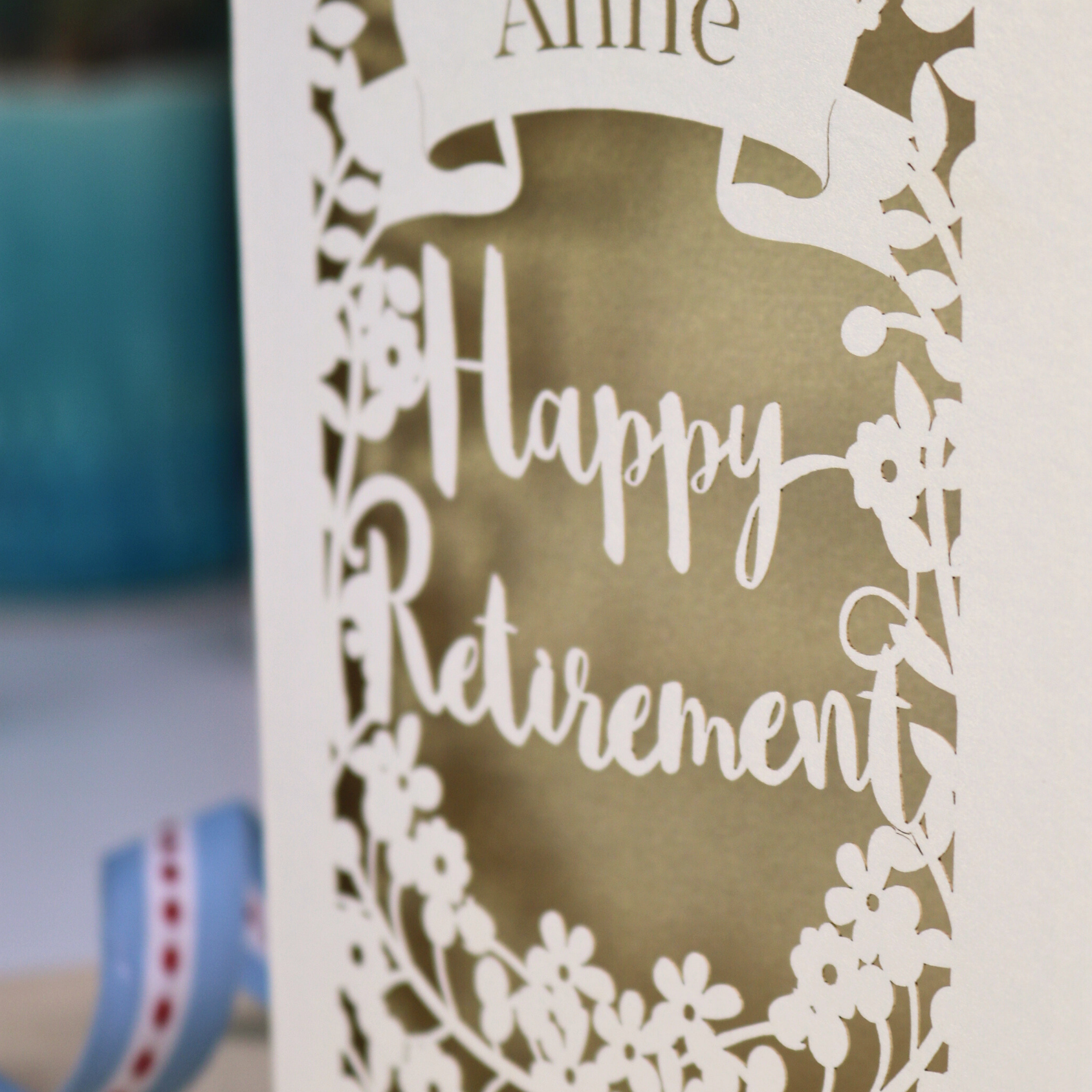 Laser-cut 'Happy Retirement' card with decorative elements on a blurred background