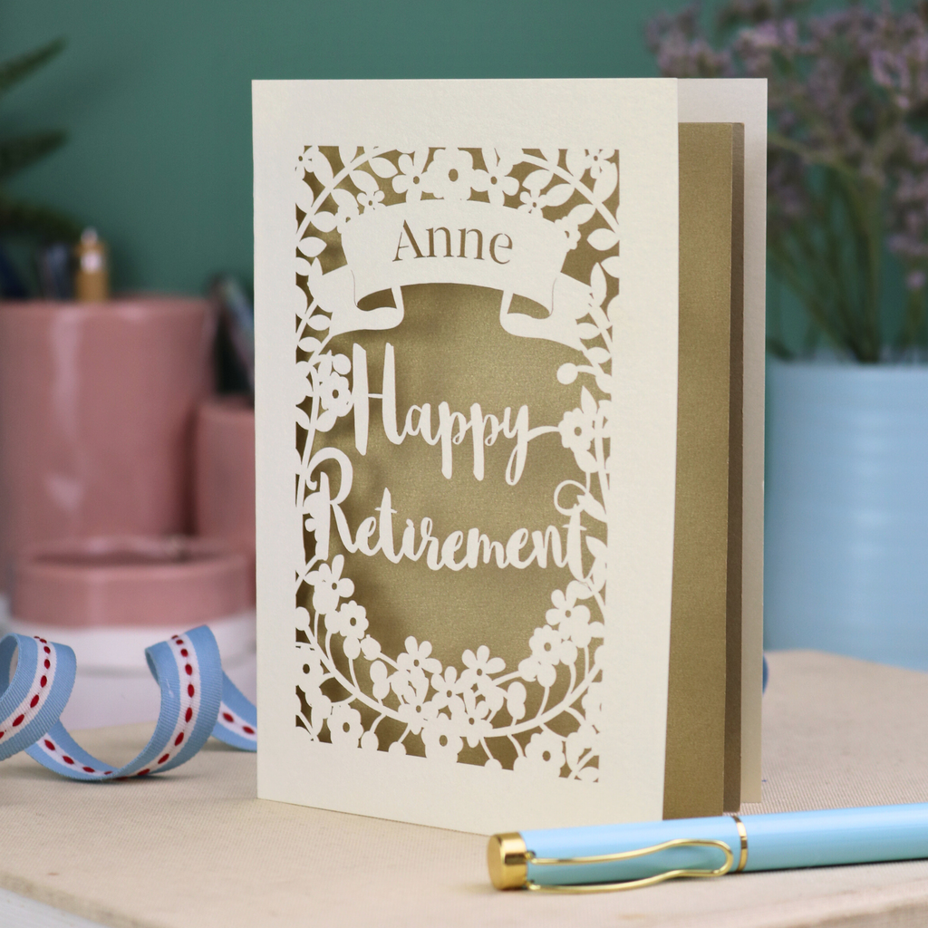Personalized 'Happy Retirement' card with decorative cut-out design on a table.