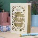 Personalized 'Happy Retirement' card with decorative cut-out design on a table.