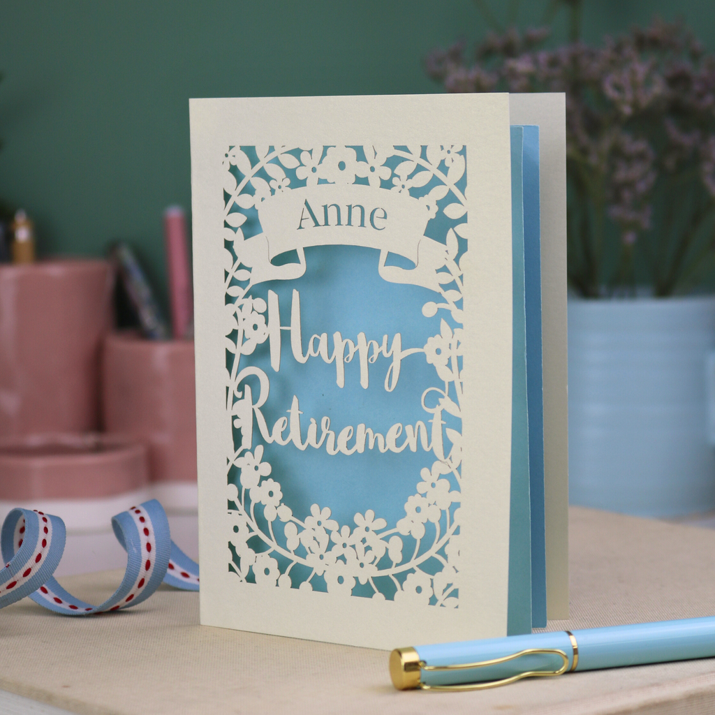 Greeting card with 'Happy Retirement' text on a wooden surface with decorative items.