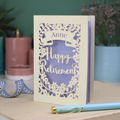 Happy Retirement card with decorative elements on a table with a pen and decorative ribbon.