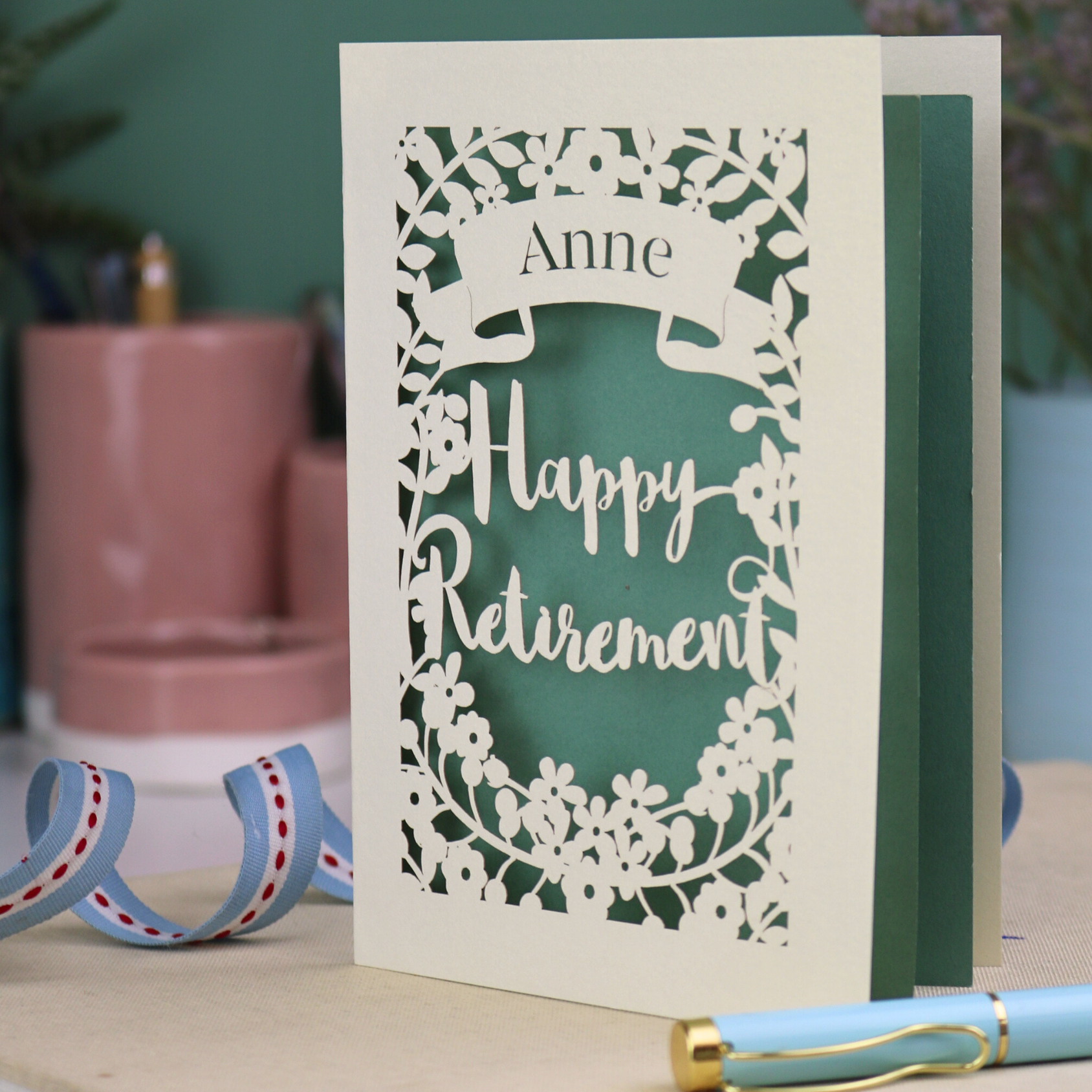 Laser cut 'Happy Retirement' card with personalized name on a blurred background