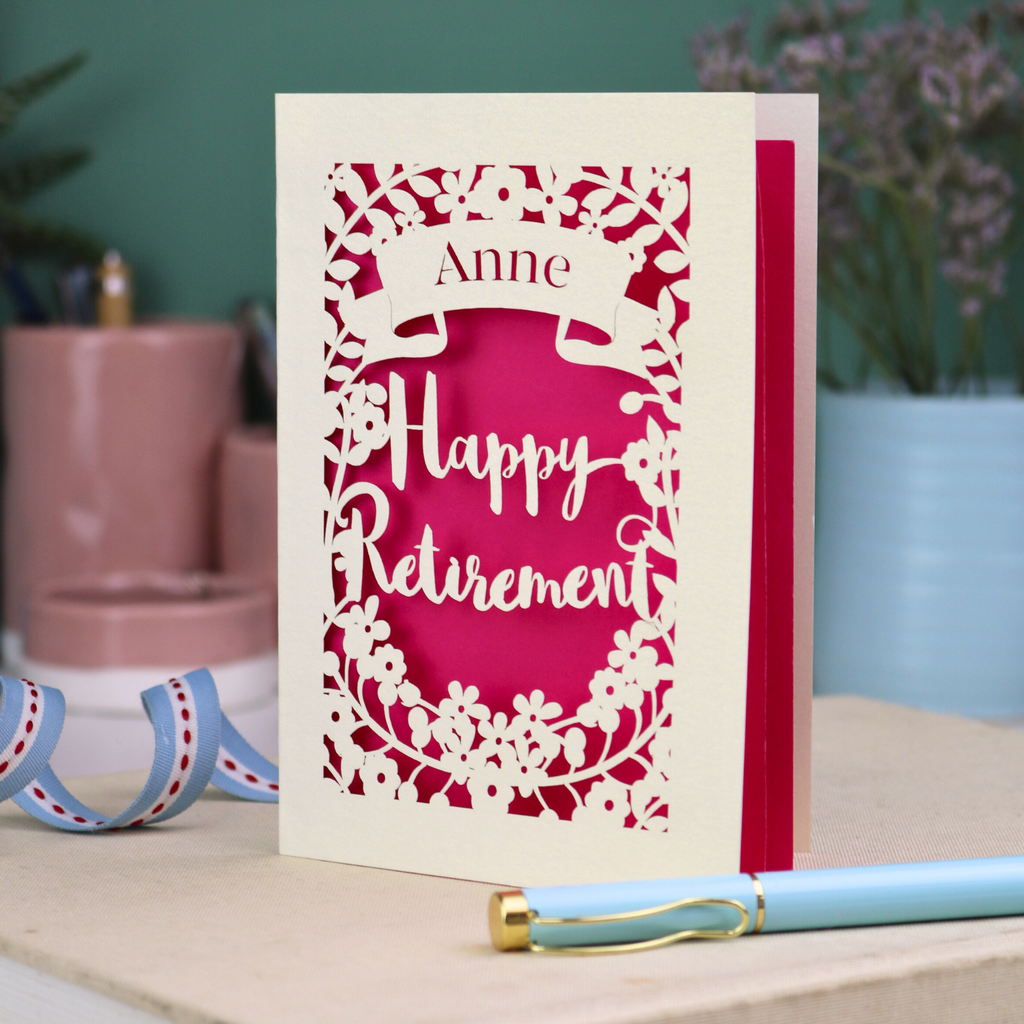 Happy Retirement card with decorative border on a table with stationery items.