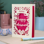 Happy Retirement card with decorative border on a table with stationery items.