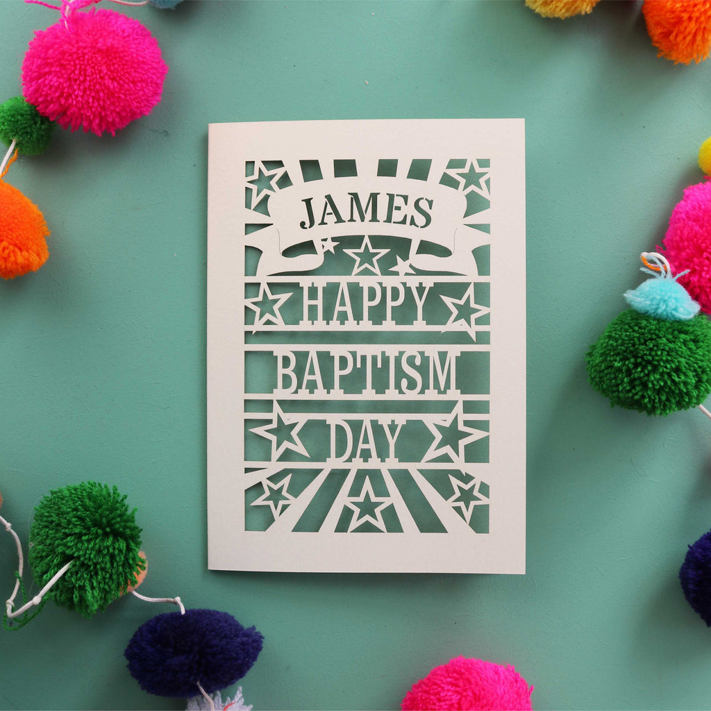 A laser cut Baptism card that is personalised with a first name in a banner and reads "Happy Baptism Day"