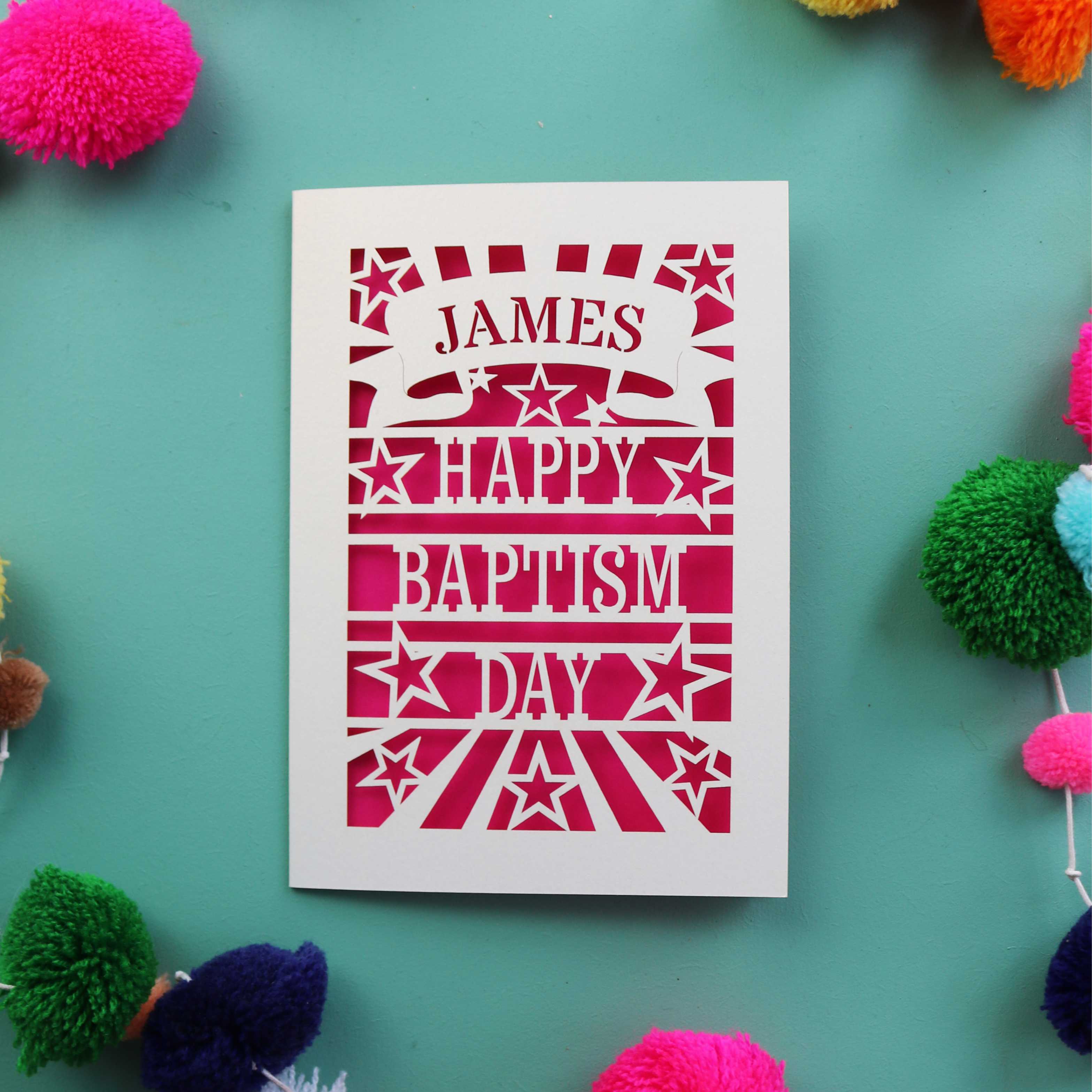 A laser cut card that is personalised with a first name in a banner and reads "Happy Baptism Day"