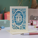 A laser cut new home card with floral border, house design and the words "Home sweet home"
