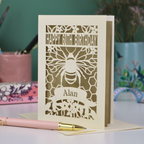Laser-cut husband birthday card with cut out bee design and 'Happy 60th Birthday Alan' text on a gold background.