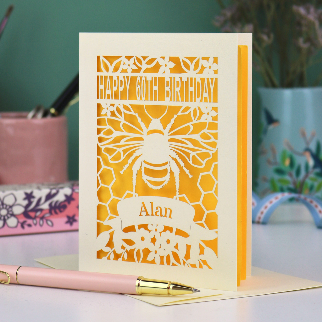 Laser-cut husband birthday card with cut out bee design and 'Happy 60th Birthday Alan' text on a yellow background.