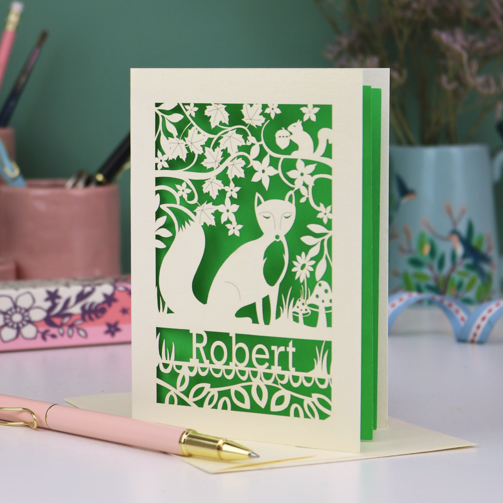 Husband Birthday Card with fox design and 'Robert' text on a desk with stationery items.