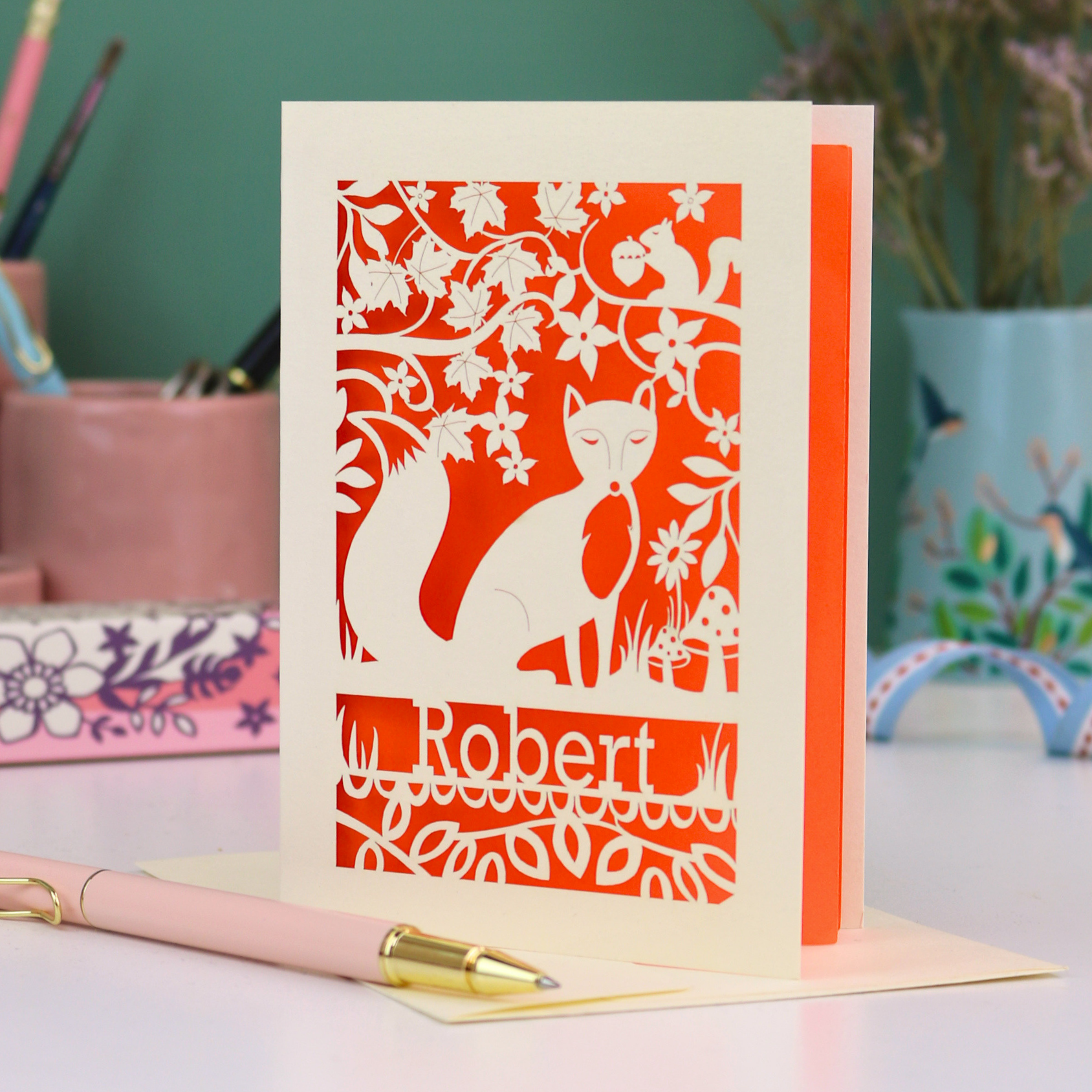 Laser cut birthday Card with fox design and 'Robert' text on a desk with stationery items.
