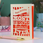 A cream and orange paper cut Husband Birthday card with cut out text design - "Happy Birthday to the most awesome husband ever"