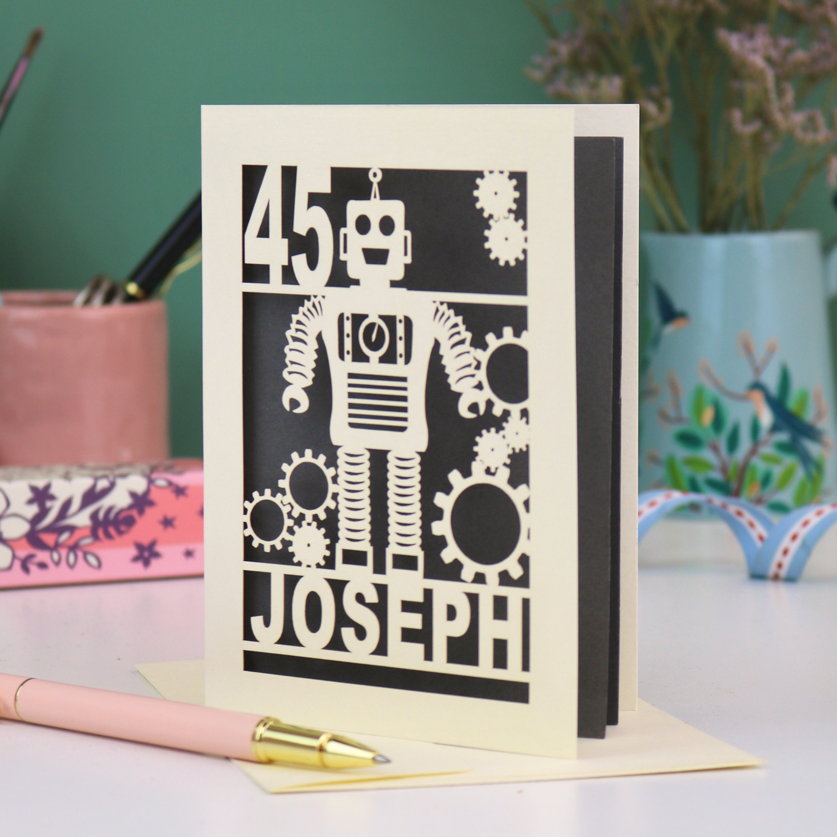 A laser cut birthday card with robot design, personalised with the age '45' and the name 'Joseph'