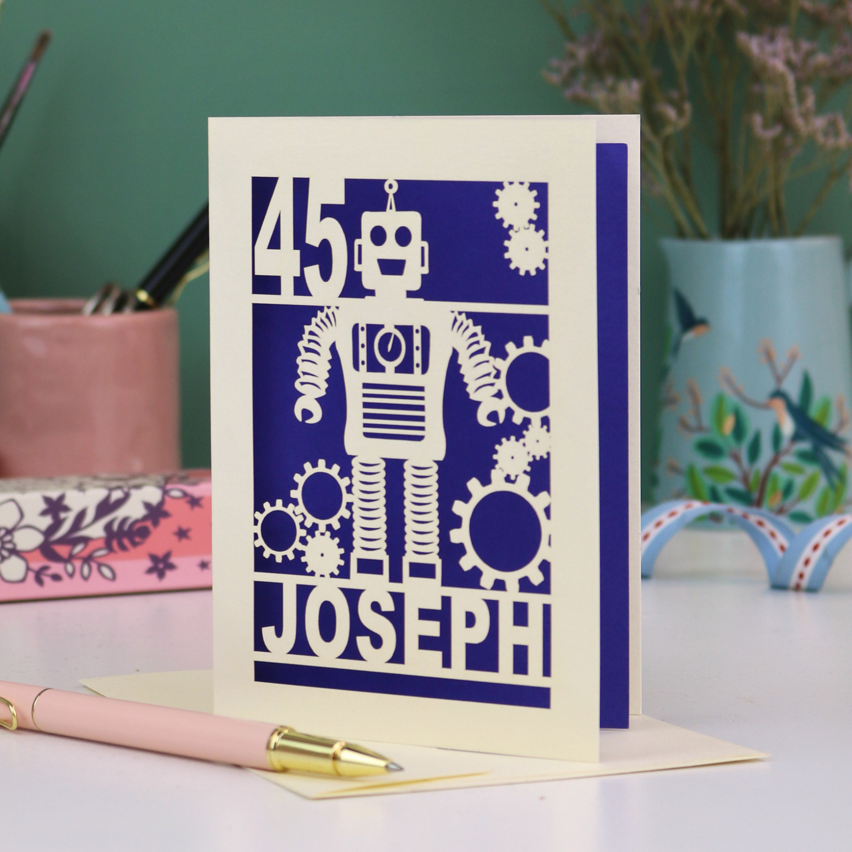 A laser cut birthday card with robot design, personalised with the age '45' and the name 'Joseph'