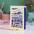 A cream and violet paper cut Husband Birthday card with cut out text design - "Happy Birthday to the most awesome husband ever"