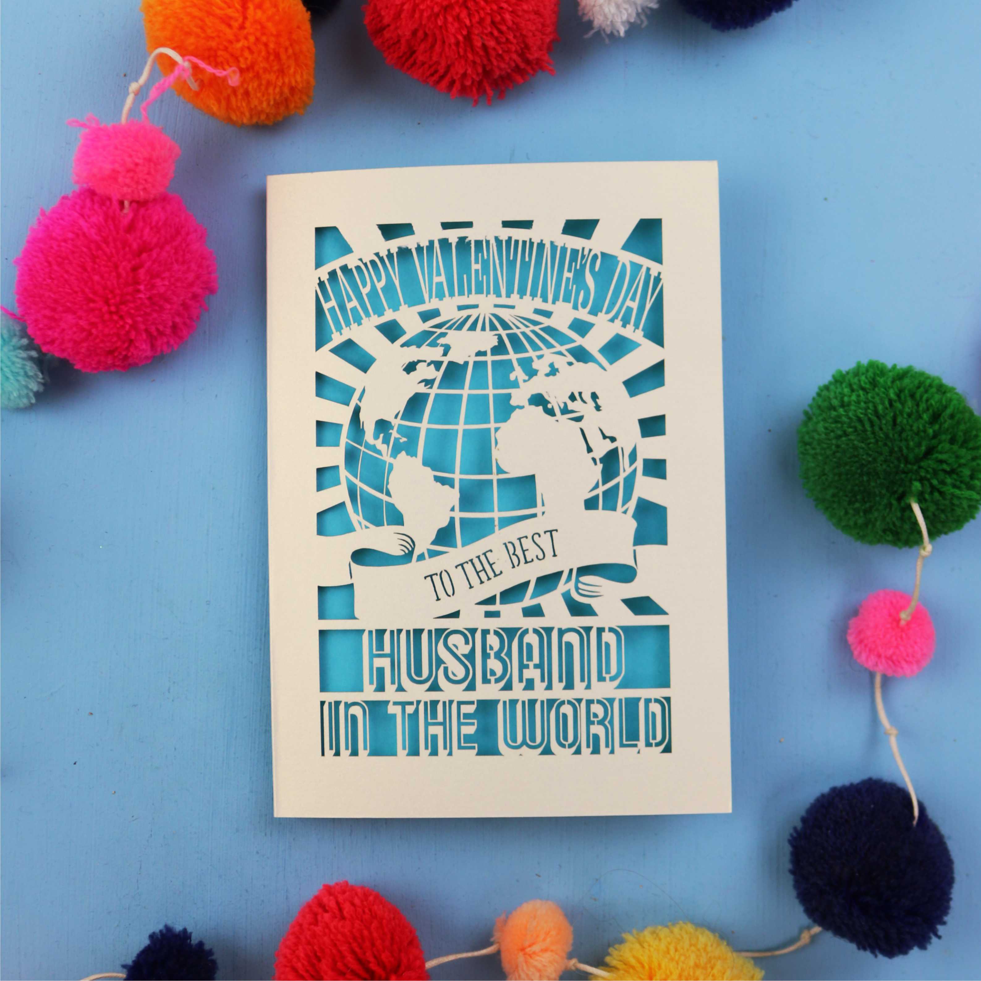 Husband Valentine's Card with 'Happy Valentine's Day' and 'To the best husband in the world' text on a blue background with colourful pom-poms.