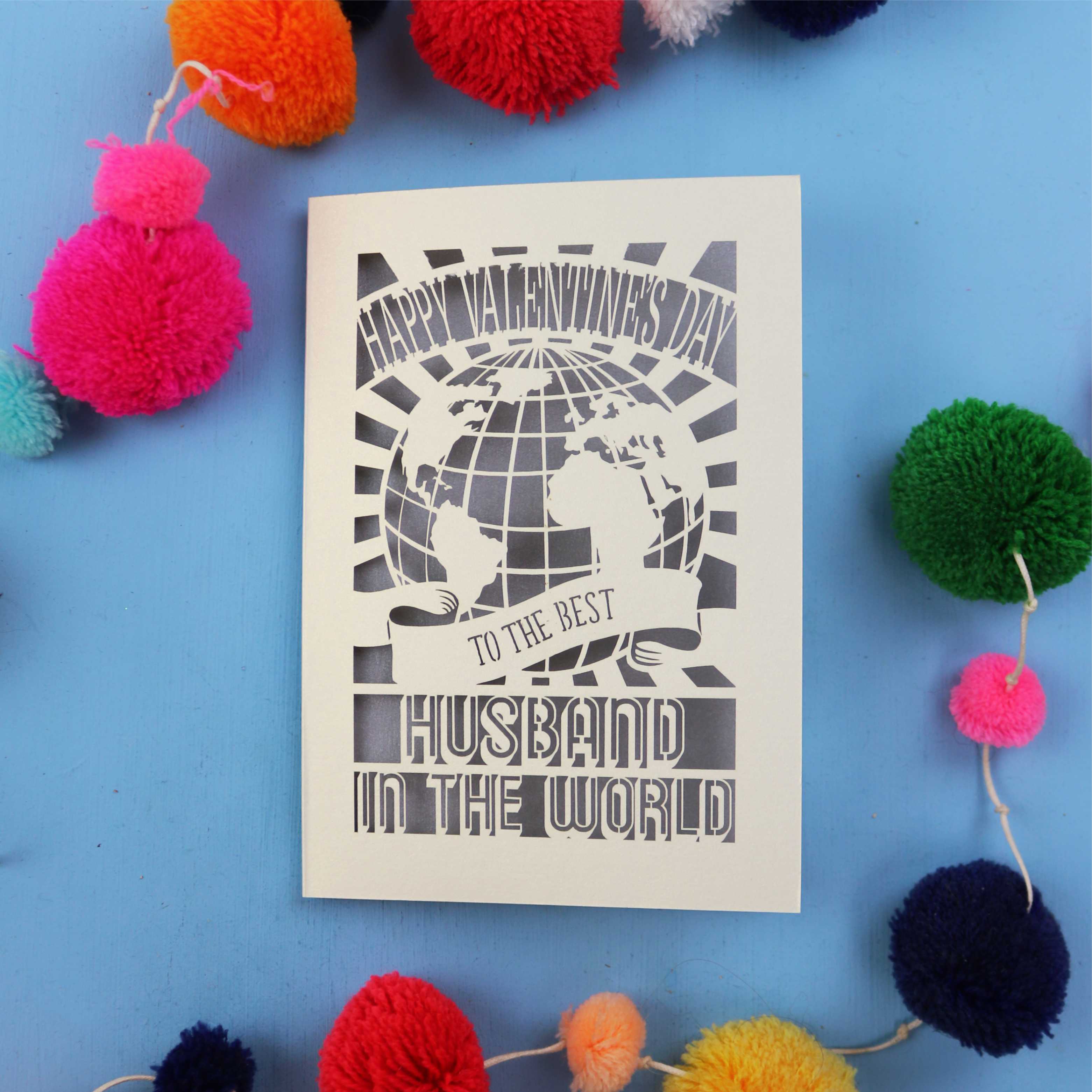 Husband Valentines Card with 'Happy Valentine's Day' and 'To the best husband in the world' text on a blue background with colourful pom-poms.