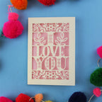 Valentine's Card with 'I LOVE YOU' design surrounded by colourful pom-poms on a blue background