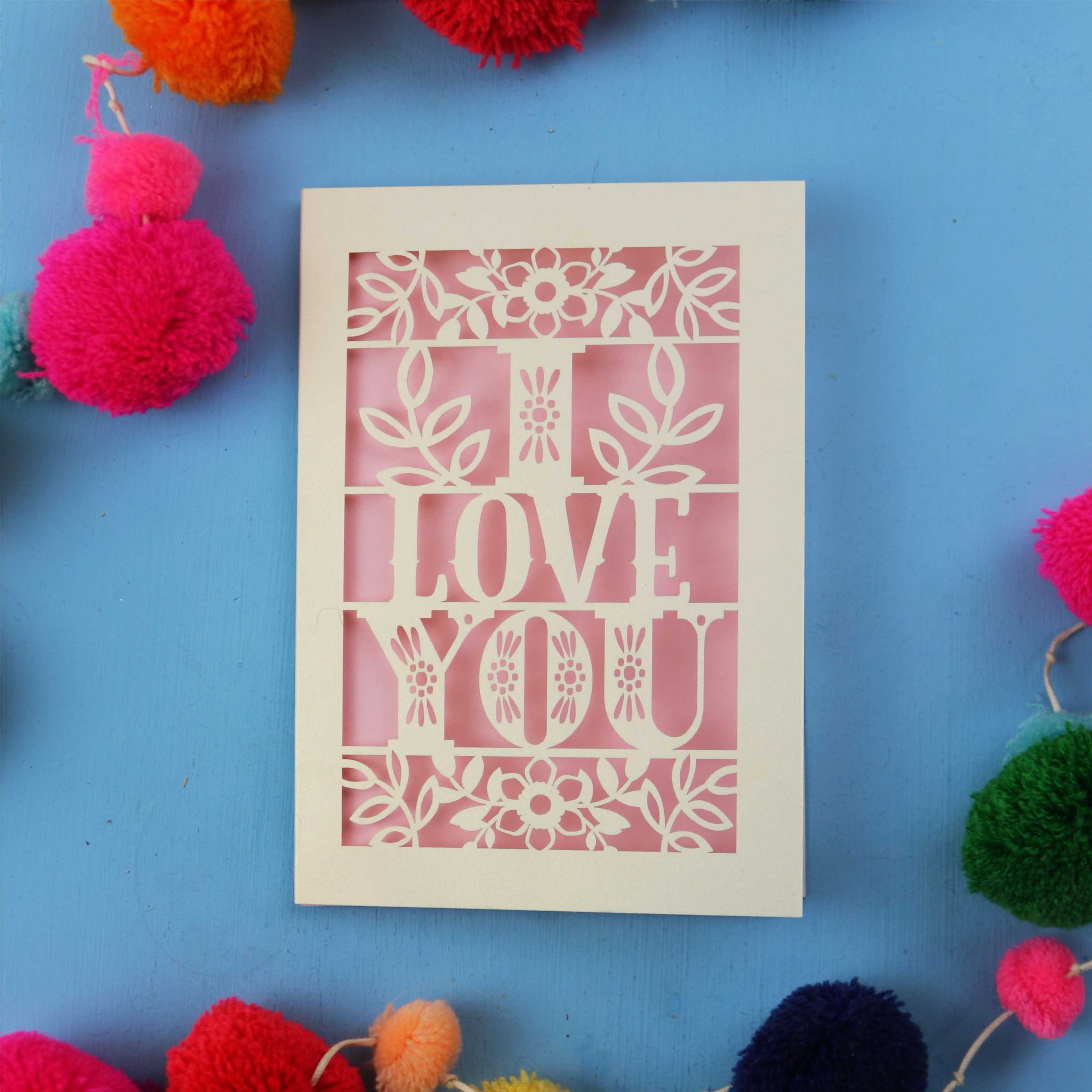 Valentine's Card with 'I LOVE YOU' design surrounded by colourful pom-poms on a blue background