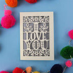 Valentine's Card with 'I LOVE YOU' design surrounded by colourful pom-poms on a blue background