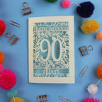 Birthday card with 'Happy Birthday 90 Albert' on a blue background with colourful pom-poms and paper clips.