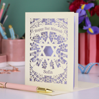 Personalized Happy Bat Mitzvah card with decorative design on a desk with stationery items.