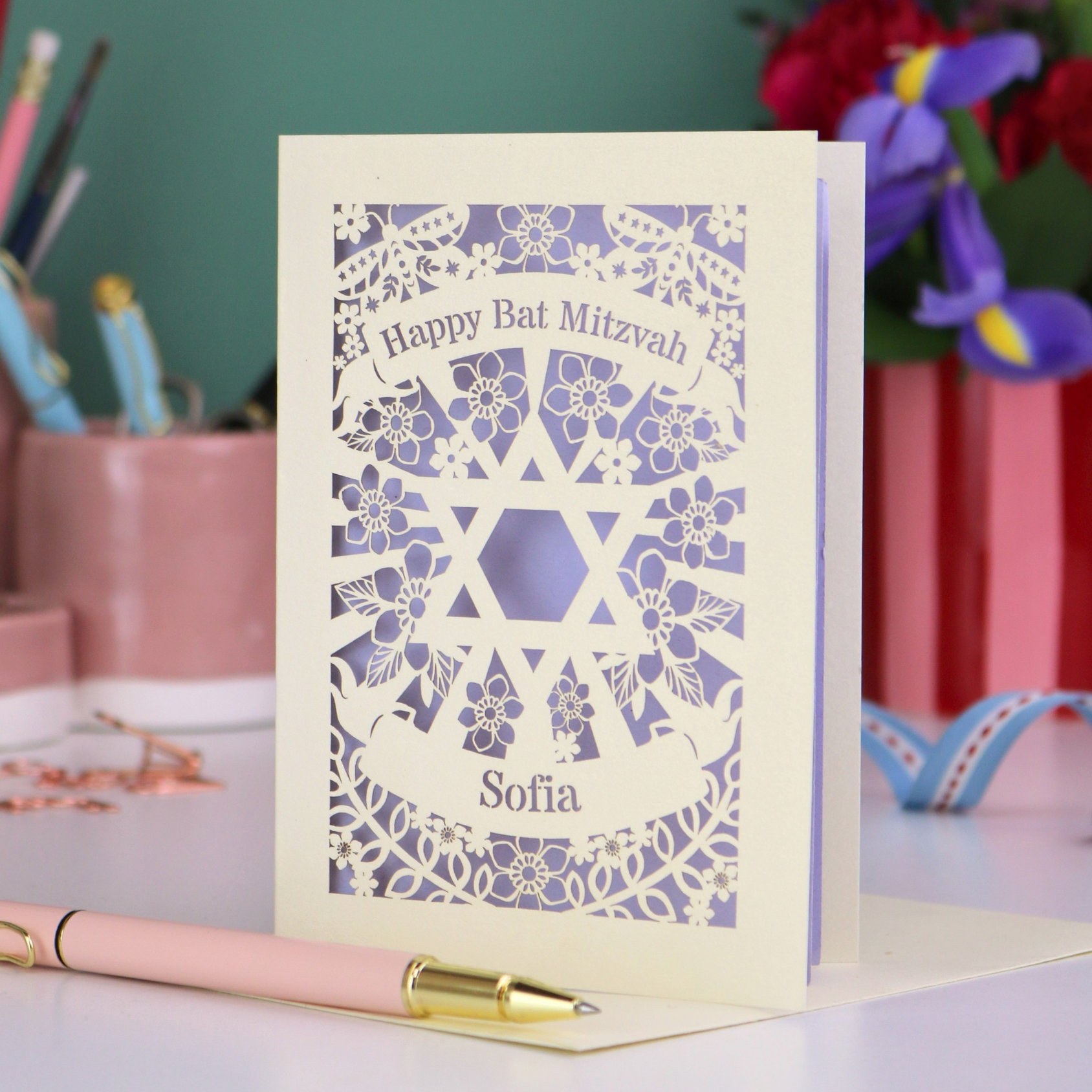 Personalized Happy Bat Mitzvah card with decorative design on a desk with stationery items.