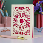 Personalized Bat Mitzvah card with decorative patterns on a desk with stationery items.