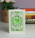 Kindness is everything  lasercut card. Cut from cream card with a bright green insert. Butterflies and lots of flowers around a central heart with the text in two banners above and below the heart.