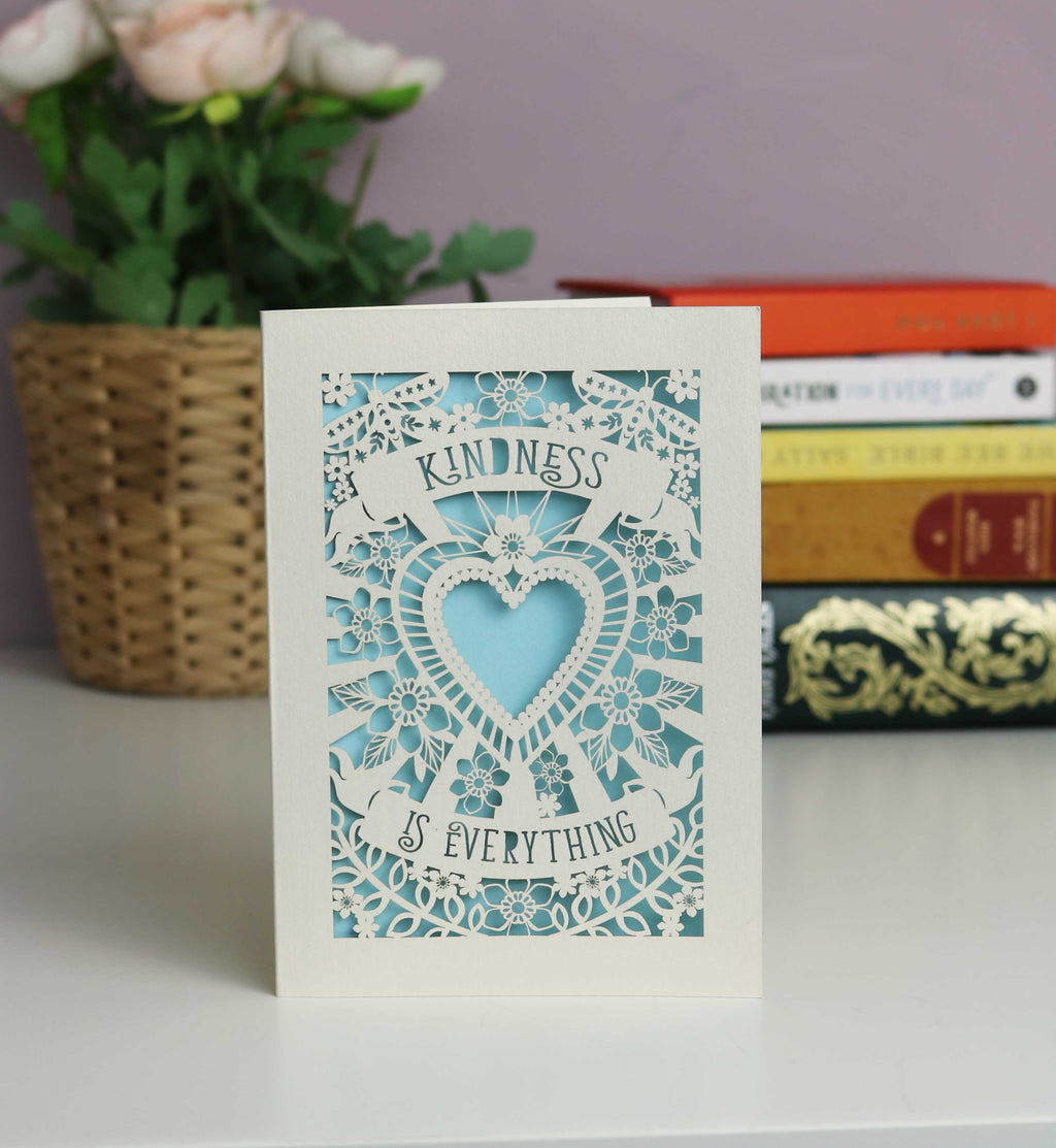 "Kindness is everything " shown on two banners above and below a beautiful cutout heart, with flowers and butterflies. Lovely pale blue insert with cream card.