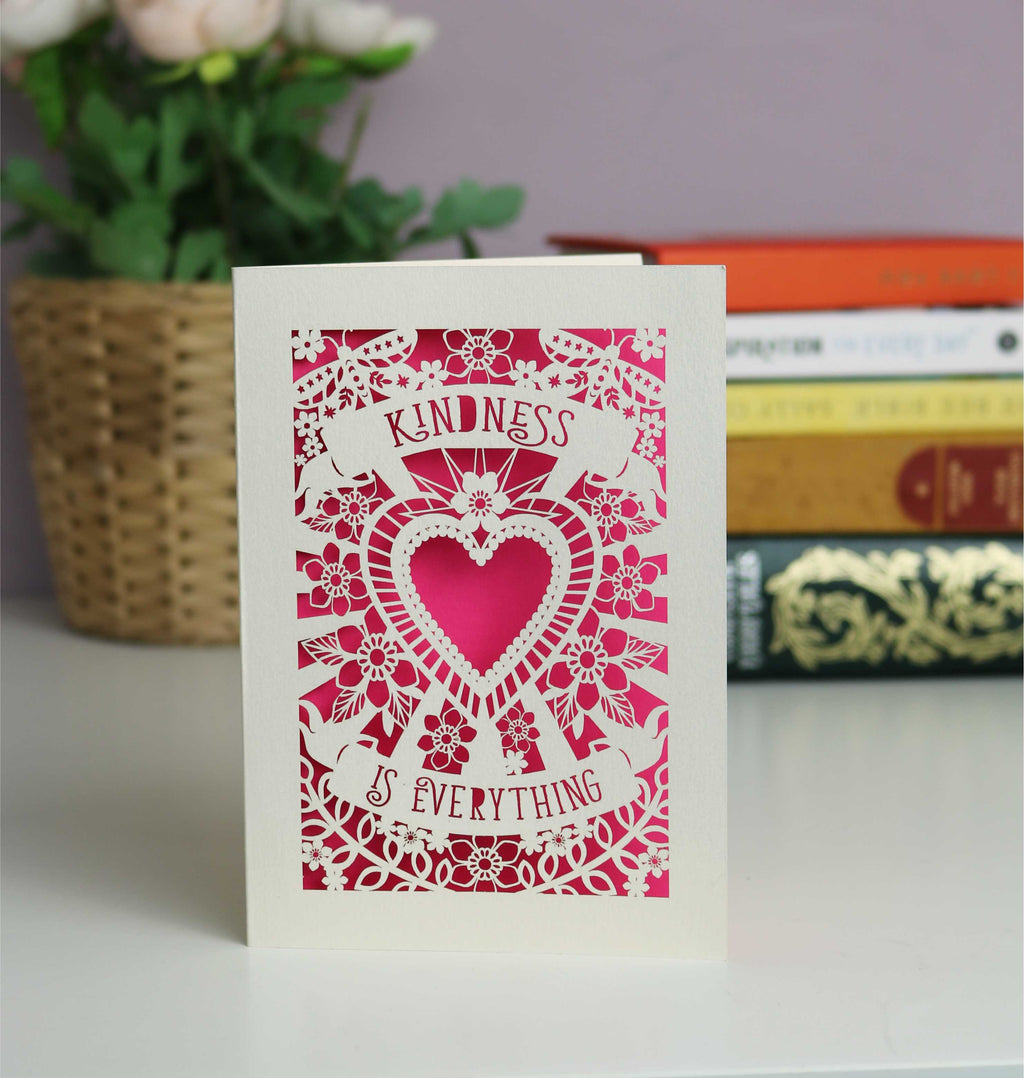 Lasercut cream and shocking pink Kindness is everything card. Flowers, butterflies and a large heart with two banners containing the text.