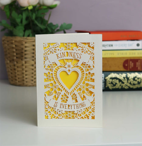 Sunshine yellow background with a cream lasercut card. Shows a heart with banners above that say "Kindness is everything"  with lots of flowers and a couple of butterflies  - A5 (large) / Sunshine Yellow