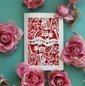 A laser cut Valentine's card with a King of Hearts theme, displayed with pink roses around it.