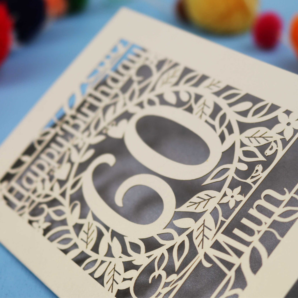 Decorative laser cut birthday card with cut-out numbers '60' and floral patterns on a blue background